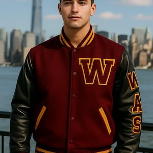 May include: Maroon and black varsity jacket with gold detailing. The jacket has a large "W" on the chest and "WAS" on the sleeve. It features black leather sleeves and gold and maroon striped trim.