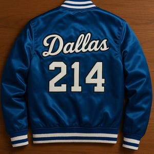 May include: A royal blue satin jacket with white and blue striped trim. The word "Dallas" is arched across the back in white script above the number "214" in white block letters.
