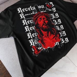 May include: Black t-shirt featuring a red graphic of Jesus wearing a crown of thorns, with butterflies and the text "Revelation 3:9" in white. The shirt is made of a soft material and is suitable for casual wear.
