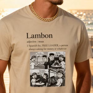 May include: A beige t-shirt with the word "Lambon" printed on it, along with a definition and a comic strip. The shirt is worn by a person with sunglasses on their head and a gold chain necklace.
