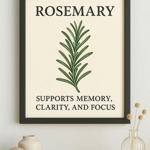 May include: A framed print with the word "ROSEMARY" at the top, above a green rosemary sprig illustration. The text below reads "SUPPORTS MEMORY, CLARITY, AND FOCUS." The artwork is in a black frame.