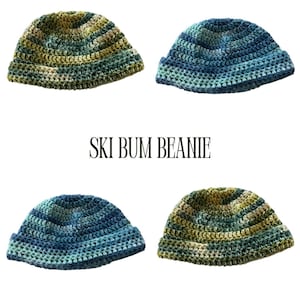 May include: Four crocheted beanies in shades of green, blue, and yellow. The beanies are arranged in a square formation. The text "SKI BUM BEANIE" is printed in a serif font below the beanies.