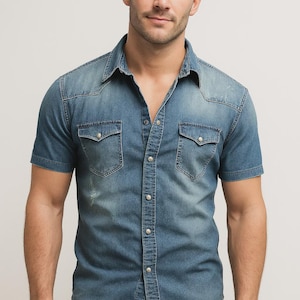 May include: Short-sleeved denim shirt in a medium blue wash. Features two chest pockets with button closures, a classic collar, and a button-down front. The shirt has a slightly distressed look, adding to its casual style.