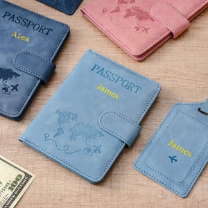 May include: A collection of passport holders in blue and pink featuring a world map design, a snap closure, and the word PASSPORT embossed on the front. Each holder is personalized with a name in yellow text, including Alex and James.