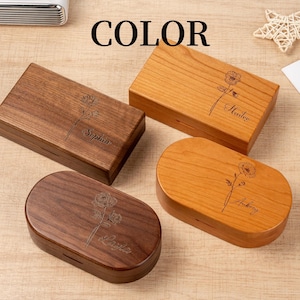 K&ouml;nnte beinhalten: Vier Holzkisten in verschiedenen Formen und Farben. Zwei sind rechteckig und zwei oval. Jede Box hat ein Blumendesign und einen Namen auf der Oberseite eingraviert. Das Wort "COLOR" ist oben im Bild in Schwarz gedruckt.