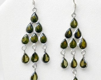 May include: A pair of chandelier earrings featuring multiple teardrop-shaped olive green gemstones set in silver metal. Each earring consists of a tiered arrangement of stones suspended from a silver hook, creating a cascading, symmetrical design.