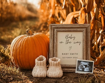 Könnte beinhalten: Ein orangefarbener Kürbis steht neben einem gerahmten Schild mit der Aufschrift "Baby on the way", einem Herz, dem Namen "Baby Smith" und dem Monat "Oktober 202X". Zwei kleine, cremefarbene gestrickte Babyschuhe befinden sich vor dem Kürbis. Ein Ultraschallbild befindet sich neben dem Rahmen.