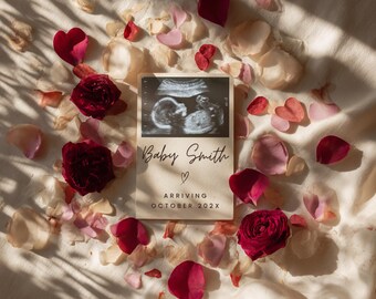 May include: A pregnancy announcement card with a sonogram image, the text "Baby Smith", and "Arriving October 202X". The card is surrounded by red rose petals and blooms, and pink petals on a cream-colored fabric.