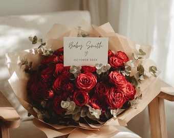 May include: A bouquet of red roses and eucalyptus leaves wrapped in brown paper, resting on a wooden chair. A white card with the text "Baby Smith" and "October 202X" is placed on top of the bouquet.