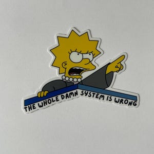 May include: A sticker depicting a cartoon character with yellow hair and a black dress, pointing and shouting. The text on the sticker reads "THE WHOLE DAMN SYSTEM IS WRONG" in white letters on a blue background.