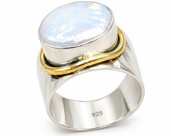 May include: A wide band ring featuring a large, oval, iridescent white pearl set in a silver bezel. A thin, polished gold-tone wire wraps around the base of the pearl setting. The interior of the silver band is clearly stamped with the number 925.