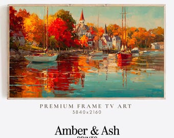 May include: A framed landscape painting depicts a harbor scene with sailboats and buildings. The artwork features vibrant autumn colors, with red and orange foliage reflected in the water. The text "PREMIUM FRAME TV ART" and "Amber & Ash PRINTS" are visible.