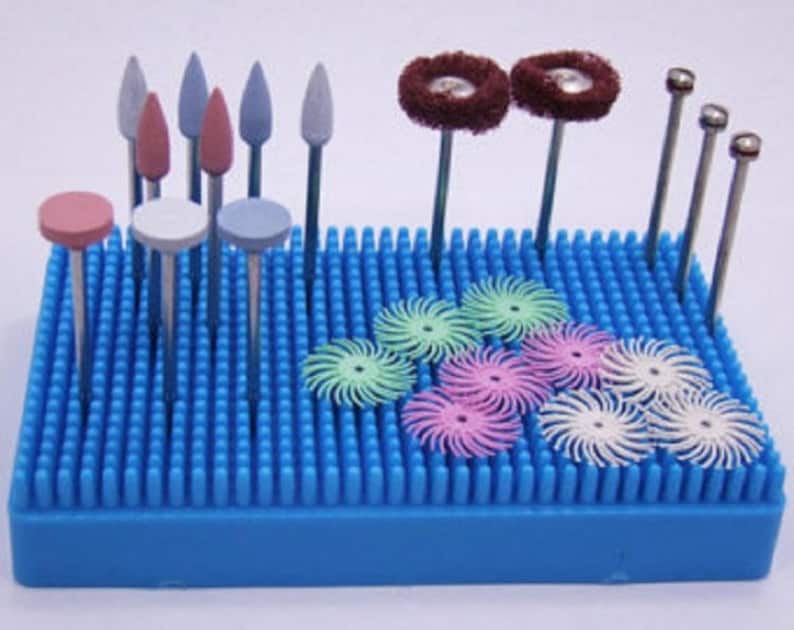 Puede incluir: Una bandeja organizadora azul llena de varias herramientas dentales. Las herramientas incluyen pulidores rosas, blancos y azules en forma de disco, puntas abrasivas en forma de cono y bala, y peque&ntilde;as herramientas met&aacute;licas de cabeza redonda. La bandeja es de color azul s&oacute;lido.