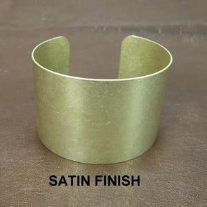 May include: A gold-toned metal bracelet with a satin finish. The bracelet is simple and elegant.