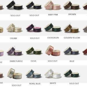 May include: A collection of sewing thread spools in various colors, including baby pink, brown, and burgundy. Each spool is paired with a matching bobbin. Text labels indicate colors and "SOLD OUT" status.