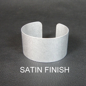 May include: A silver metal cuff bracelet with a satin finish.