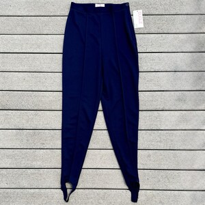 May include: Navy blue stirrup pants with a high waist and vertical seams. The pants have a button closure and a tag that reads "BUGLE". The stirrups are designed to be worn under the foot.