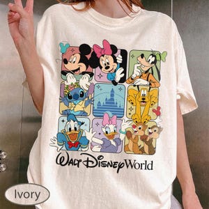 May include: Ivory-colored t-shirt featuring a grid of Disney characters including Mickey Mouse, Minnie Mouse, Goofy, Stitch, Pluto, Donald Duck, Daisy Duck, Chip and Dale. The words "Walt Disney World" are printed below the grid.