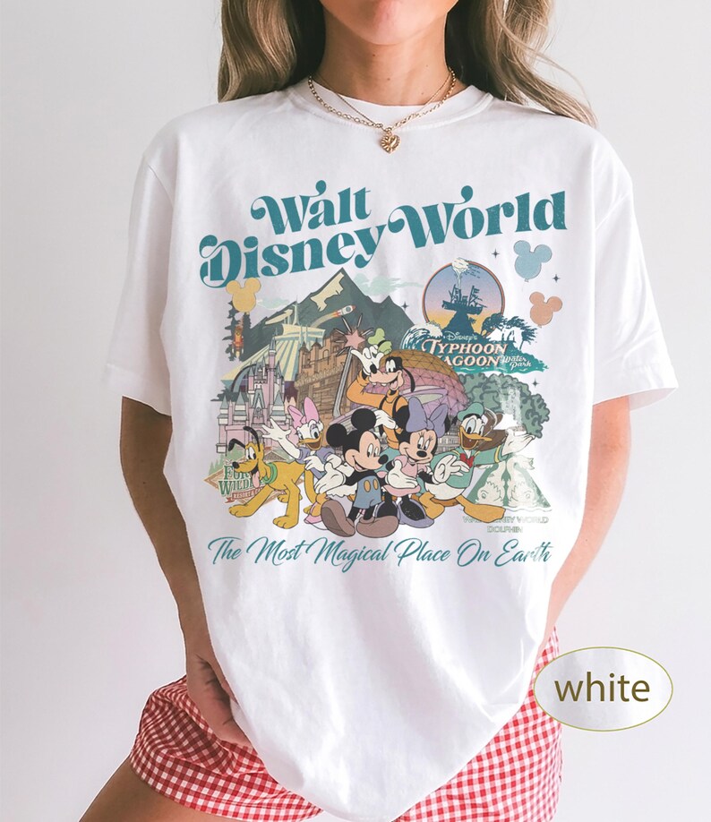 May include: White t-shirt featuring a colorful graphic of Disney characters and the text "Walt Disney World" and "The Most Magical Place On Earth". The design includes Mickey Mouse, Donald Duck, and Goofy.