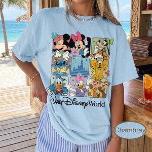 May include: Light blue t-shirt featuring a grid of Disney characters including Mickey Mouse, Minnie Mouse, Goofy, Stitch, Donald Duck, Daisy Duck, Pluto, and Chip and Dale. The words "Walt Disney World" are printed below the grid.