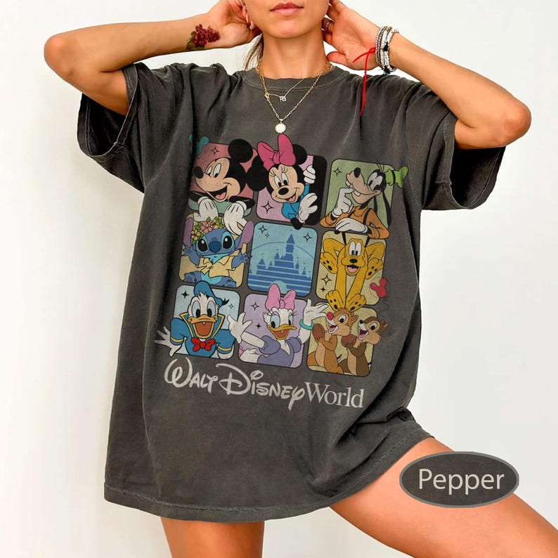 May include: Dark gray t-shirt featuring a colorful graphic of Disney characters in square frames. The shirt includes Mickey Mouse, Minnie Mouse, Goofy, Stitch, Donald Duck, Daisy Duck, and Chip and Dale. The text "Walt Disney World" is printed below the characters.