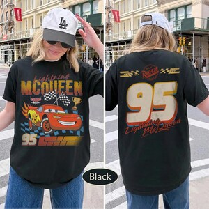 May include: Black t-shirt featuring Lightning McQueen from the Cars movie. The front design includes the character, the number 95, and the text "Lightning McQueen." The back displays the number 95 and the text "Lightning McQueen."
