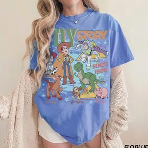 Puede incluir: Camiseta azul con personajes de la pel&iacute;cula animada "Toy Story". El dise&ntilde;o incluye a Woody, Buzz Lightyear, Rex, Slinky Dog, Hamm y Bullseye, con el texto "Toy Story Since 1995."