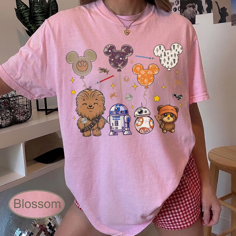 May include: Pink t-shirt featuring Star Wars characters and Mickey Mouse-shaped balloons. The design includes Chewbacca, R2-D2, BB-8, and an Ewok. The word "Blossom" is printed at the bottom of the image.