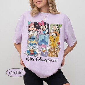 May include: Orchid-colored t-shirt featuring a grid of Disney characters including Mickey Mouse, Minnie Mouse, Goofy, Stitch, Donald Duck, Daisy Duck, and Chip and Dale. The words "Walt Disney World" are printed below the grid.