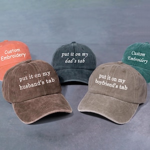 Peut inclure: Plusieurs casquettes de baseball de couleurs variées, notamment orange, marron, vert et gris. Chaque casquette arbore un texte brodé en blanc, avec des phrases comme "put it on my husband's tab" et "put it on my boyfriend's tab".