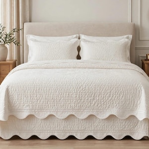 May include: A white bedspread with a textured quilted pattern and a scalloped edge, paired with two matching rectangular pillow shams. The bedding set features a consistent stitched design across the surface, creating a uniform appearance.