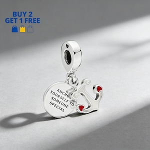May include: A silver charm with an anchor design and the words "ANCHOR YOURSELF TO SOMEONE SPECIAL" on a round pendant. The anchor has red heart accents. The charm is designed to be a pendant or bead.