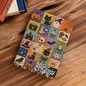 May include: A rectangular notebook cover featuring a grid of colorful Halloween-themed illustrations including pumpkins, ghosts, black cats, a skull, a haunted house, and a spider web. The name Faye is printed in white script at the bottom right.