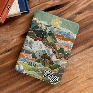 May include: A rectangular e-reader cover featuring a collage-style landscape illustration of layered mountains, green hills, and a yellow sun. The word Faye is printed in a white cursive script at the bottom right corner of the cover.