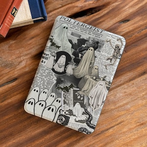 May include: A rectangular e-reader cover featuring a black and white collage of ghosts, skeletons, bats, and snakes over a vintage newspaper background. The word POLTERGEIST is printed in large capital letters at the top of the cover design.