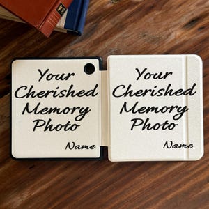 May include: A white, rectangular, folding photo frame with a black border and a circular cutout. The text "Your Cherished Memory Photo" is printed in black script, followed by the word "Name" in the bottom right corner of each panel.