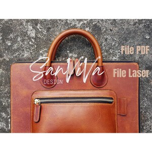Peut inclure: Une serviette en cuir marron avec une poignée supérieure et une poche avant avec une fermeture éclair. La serviette a une fermeture éclair et le texte "SanVita Design" est écrit sur le devant. Le texte "File PDF A1 A4 Letter DXF SVG" est également visible.