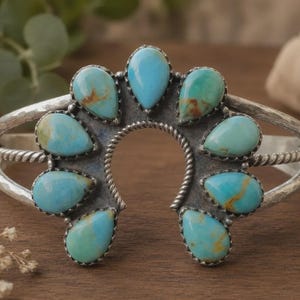 May include: A silver cuff bracelet featuring a central horseshoe-shaped frame adorned with nine teardrop-shaped turquoise stones. The metal band displays a hammered texture and twisted wire detailing, surrounding the vibrant blue-green stones.