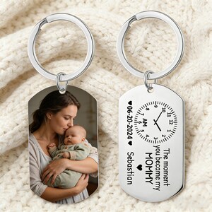 Puede incluir: Dos llaveros plateados. Uno presenta una foto de una madre y un bebé. El otro tiene un diseño de reloj con el texto "The moment you became my MOMMY" y la fecha 06-20-2024, con el nombre Sebastian.