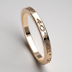 May include: A gold band ring with the numbers 4:00, 4:11, and 2:1 engraved on the outside.