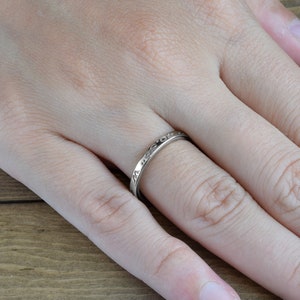 May include: A silver band ring with an inscription on the outside of the band.
