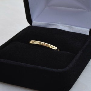 May include: A gold ring with the inscription "2' 40' 59" inside a black velvet ring box.