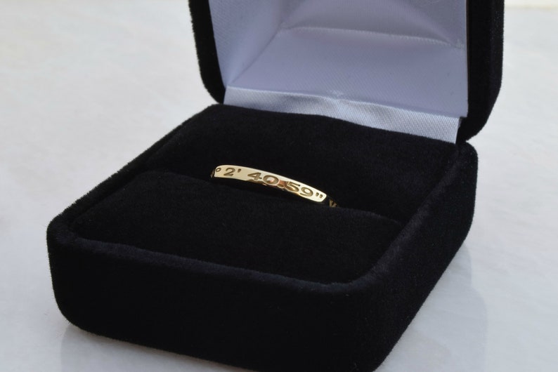 May include: A gold ring with the inscription "2' 40' 59" inside a black velvet ring box.