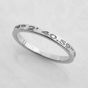 May include: A silver ring with the coordinates "40.59" 149 2' engraved around the band.