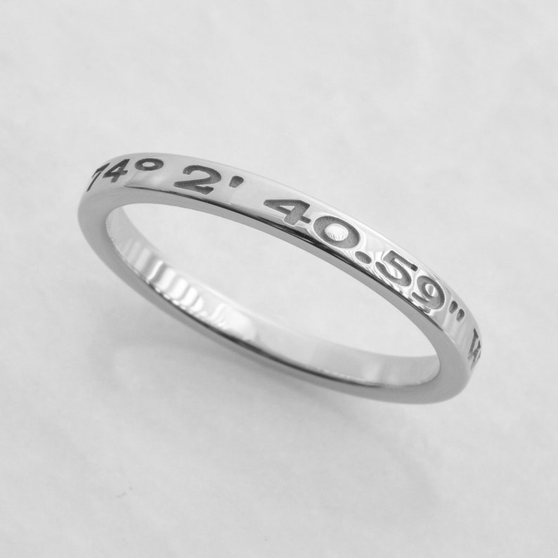 May include: A silver ring with the coordinates "40.59" 149 2' engraved around the band.