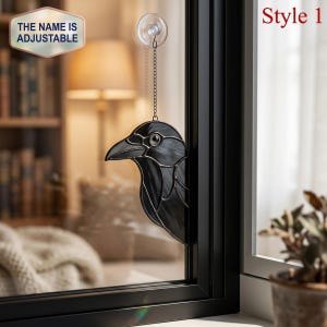 May include: Black stained glass raven window hanging. The raven is attached to a chain and suction cup. The text "Style 1" is in the upper right corner. The text "THE NAME IS ADJUSTABLE" is in the upper left corner.