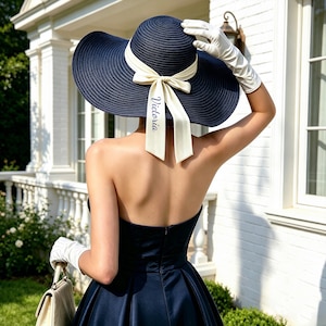 Peut inclure: Un chapeau de soleil bleu marine à large bord avec un ruban crème. Le ruban porte le nom "Victoria". Le chapeau est assorti de gants blancs et d'une robe bleu marine assortie.