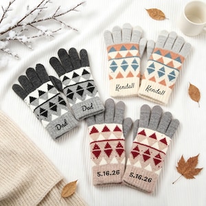 May include: Three pairs of knit gloves featuring geometric patterns in grey, white, and accent colours. One pair is grey and white with 'Dad' text, one is peach and blue with 'Kendall' text, and one is red and beige with '5.16.26' text.