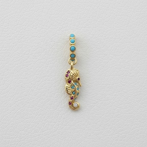 Puede incluir: Colgante de oro con forma de caballito de mar con detalles de turquesa, rubí y diamantes. El caballito de mar tiene un cuerpo curvado y un diseño detallado. El colgante cuelga de una cadena con cuentas turquesas. Una joya única.