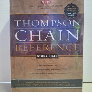 Könnte beinhalten: Ein gebundenes Buch "The Thompson Chain Reference Study Bible" in Braun- und Lilatönen. Auf dem Einband steht "The Thompson Chain Reference" und "Study Bible". Das Buch ist eine New King James Version mit über 2.400 Seiten.